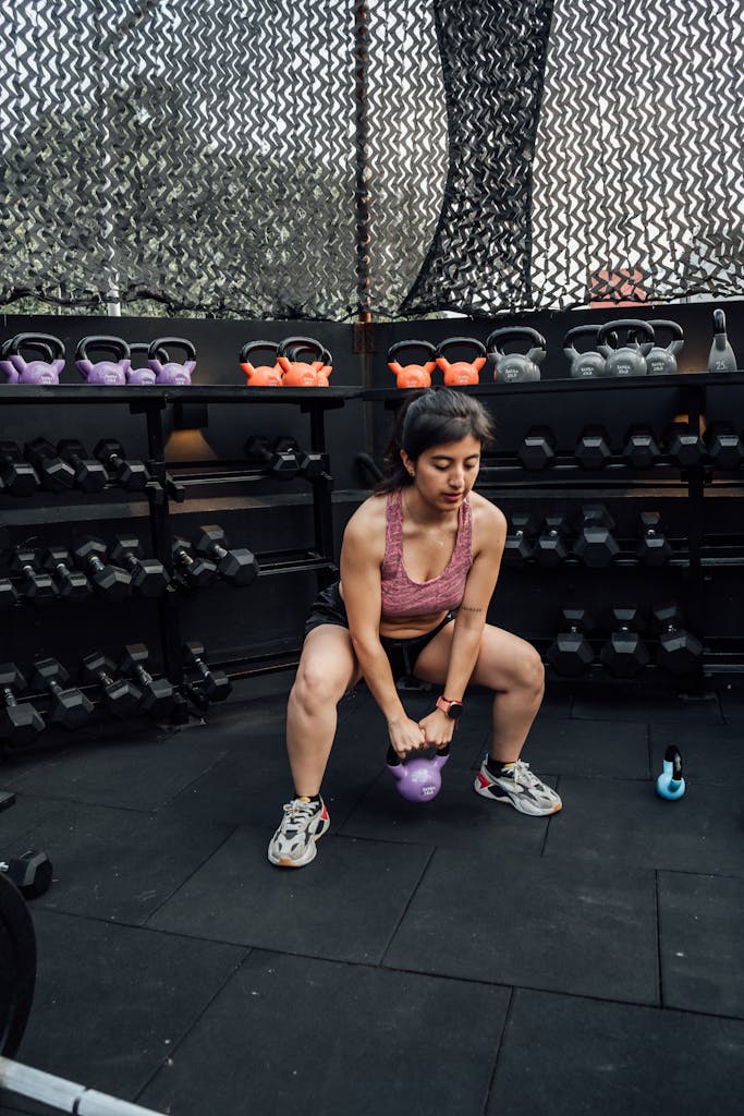Female athlete lifting kettlebell in a gym, focusing on strength and fitness, Mexico City.